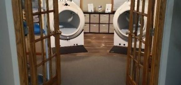 A laundry room with two washers and dryers and french doors.