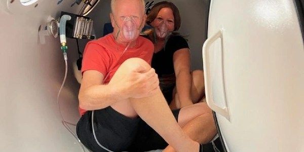 A man and a woman are sitting in an oxygen chamber.