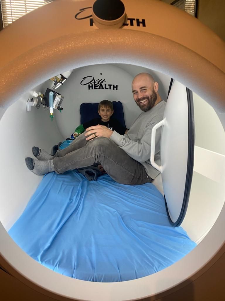 A man and a boy are sitting in an oxygen chamber.