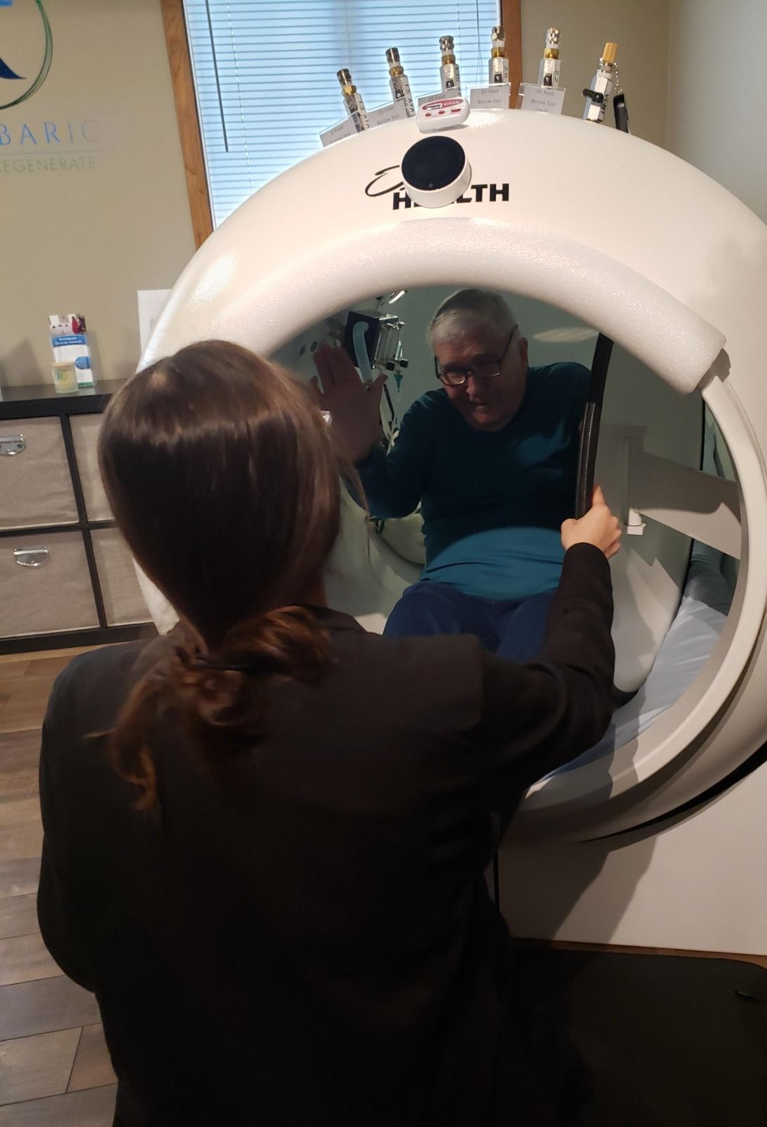 A woman is looking at a man in a machine.