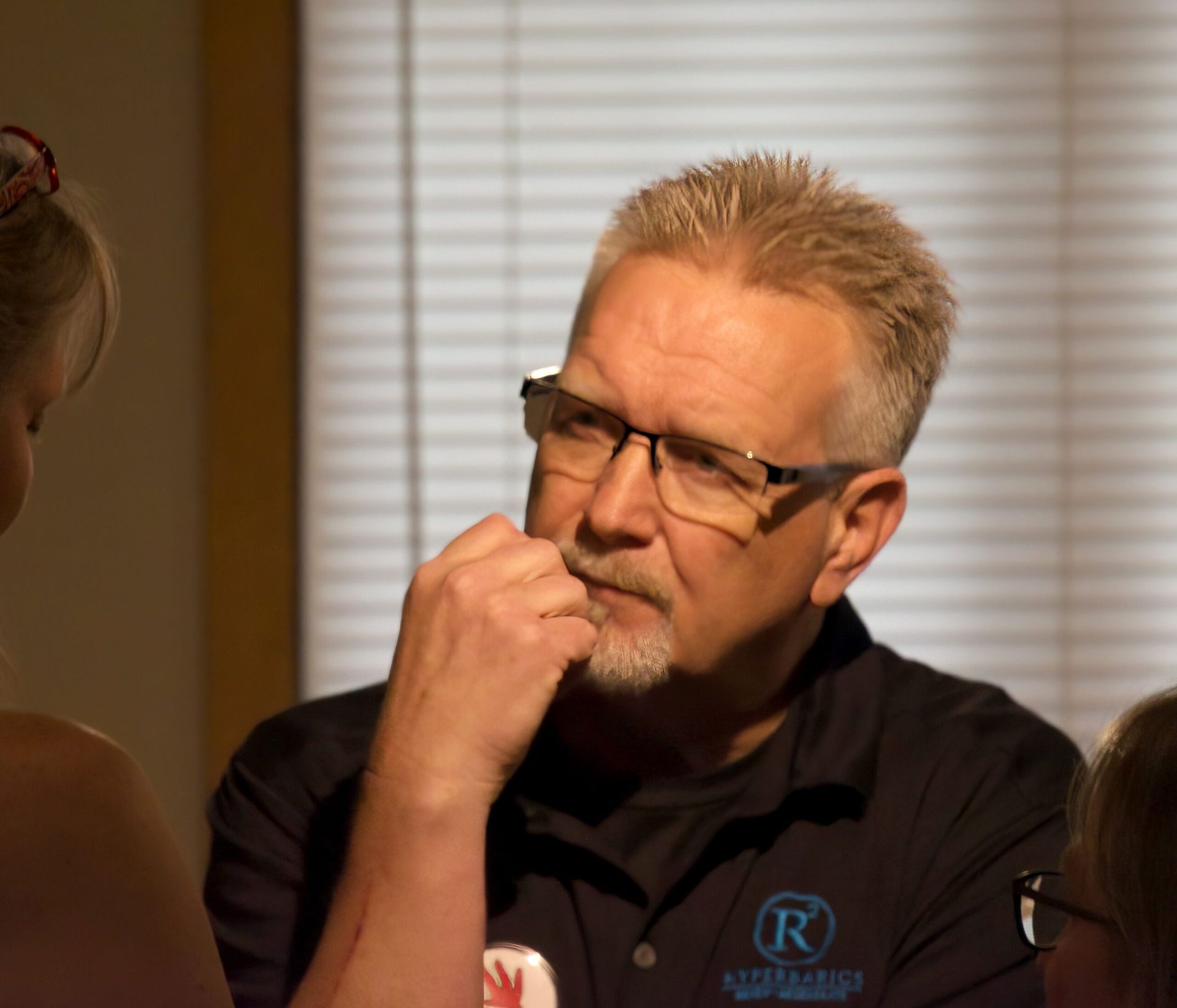 A man wearing glasses and a shirt with the letter r on it
