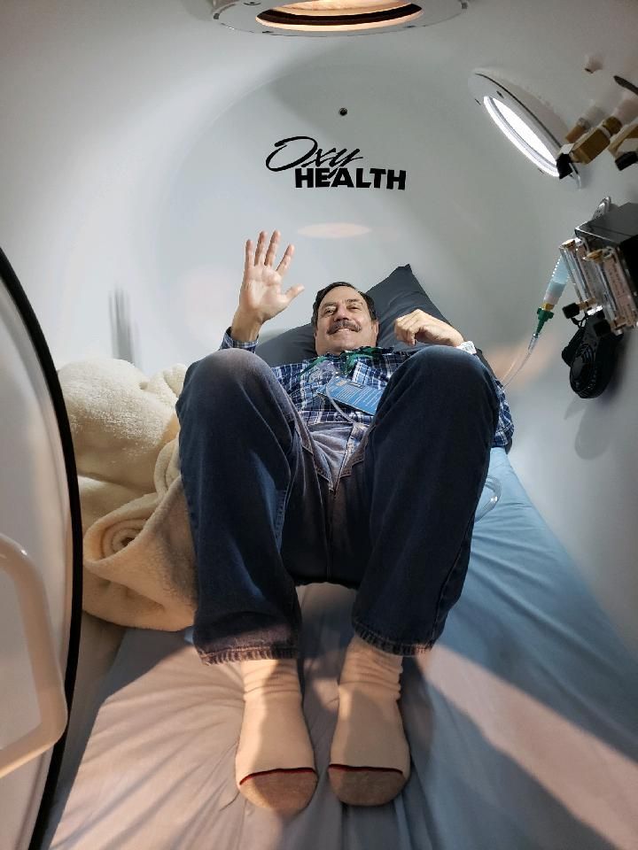 A man is laying on a bed in an oxygen chamber.
