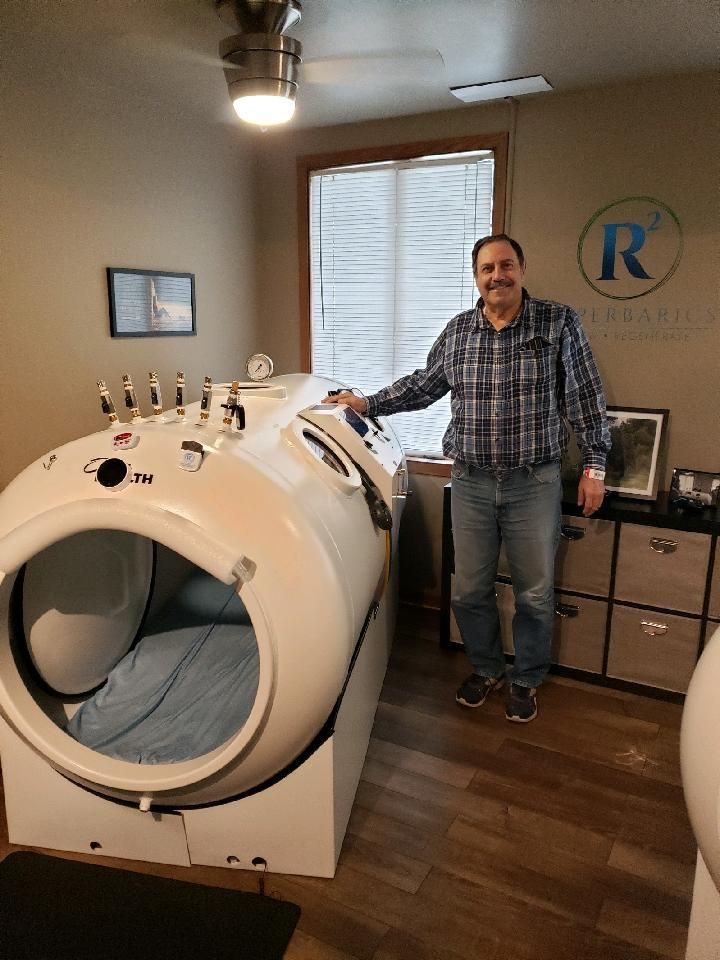 A man in a plaid shirt is standing in front of an r logo