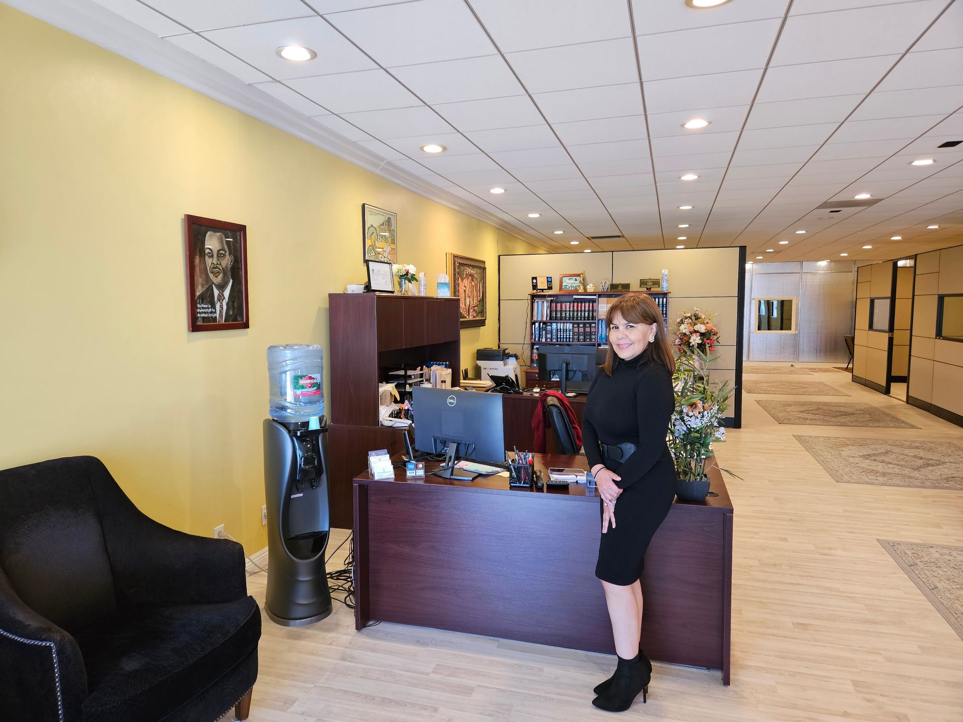 Hotel lobby with a receptionist standing behind the front desk near a water cooler and Christmas tree.