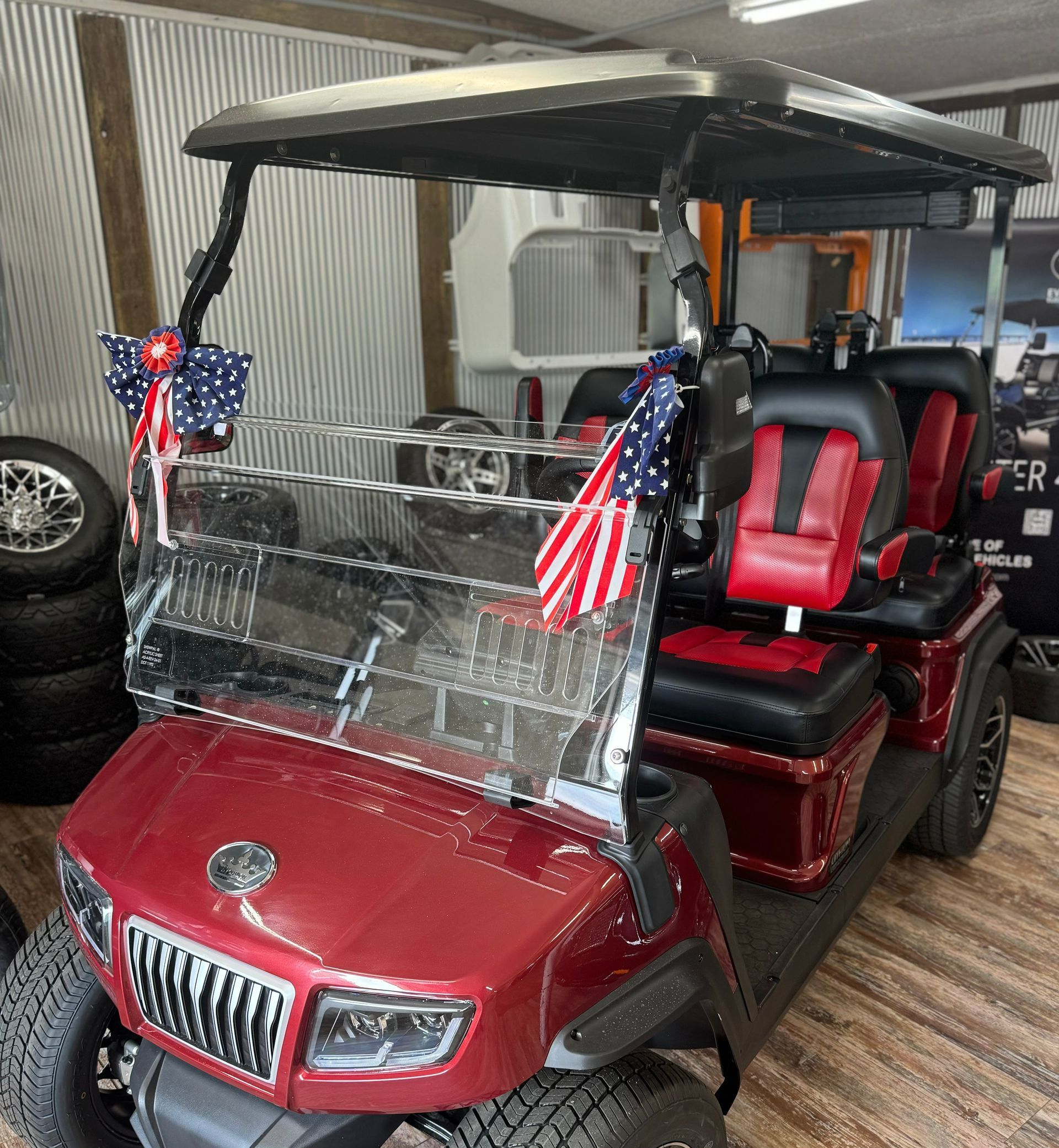 A red golf cart with an American flag on the front is parked in a garage.