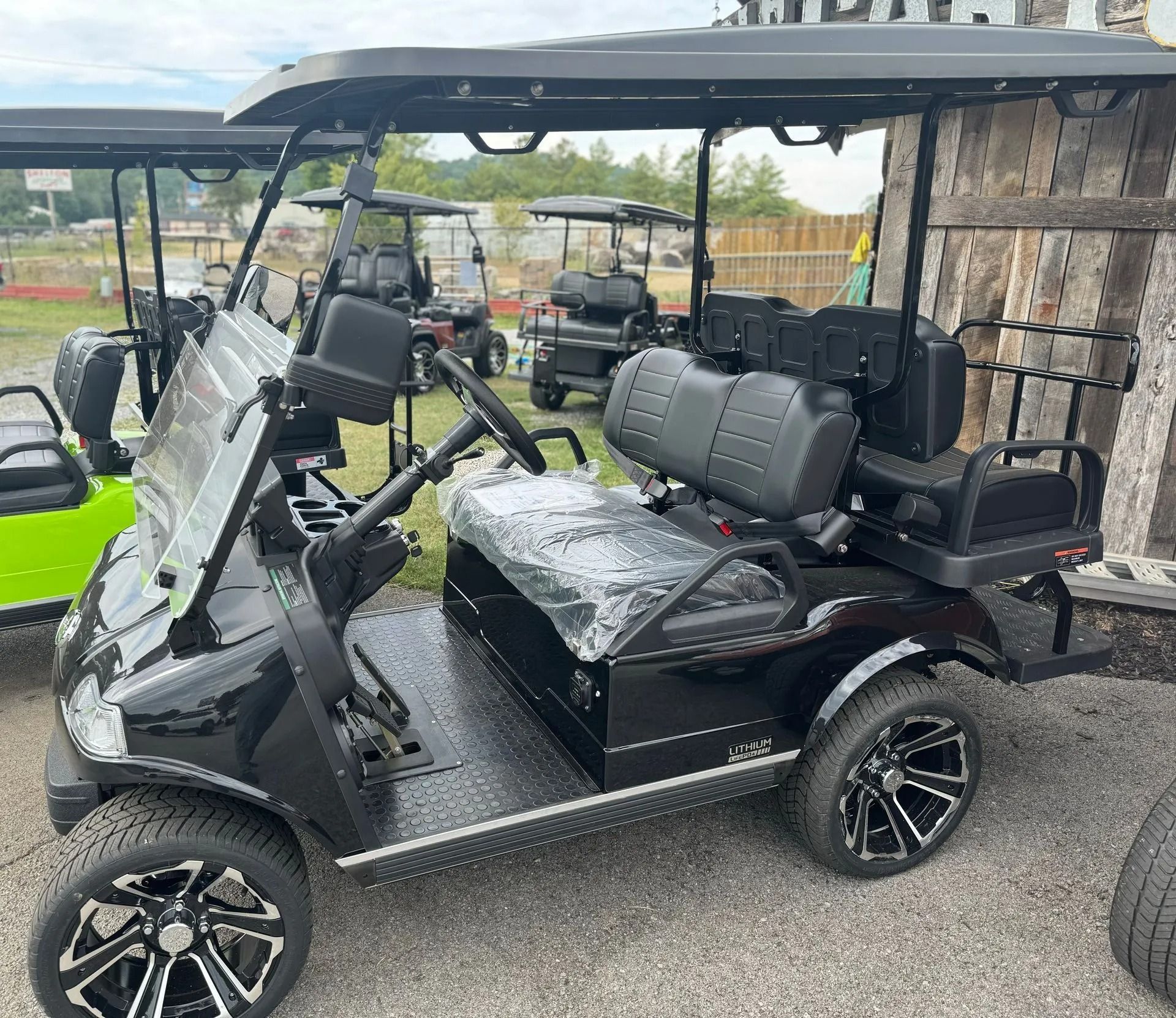 A black golf cart is parked next to a green golf cart.