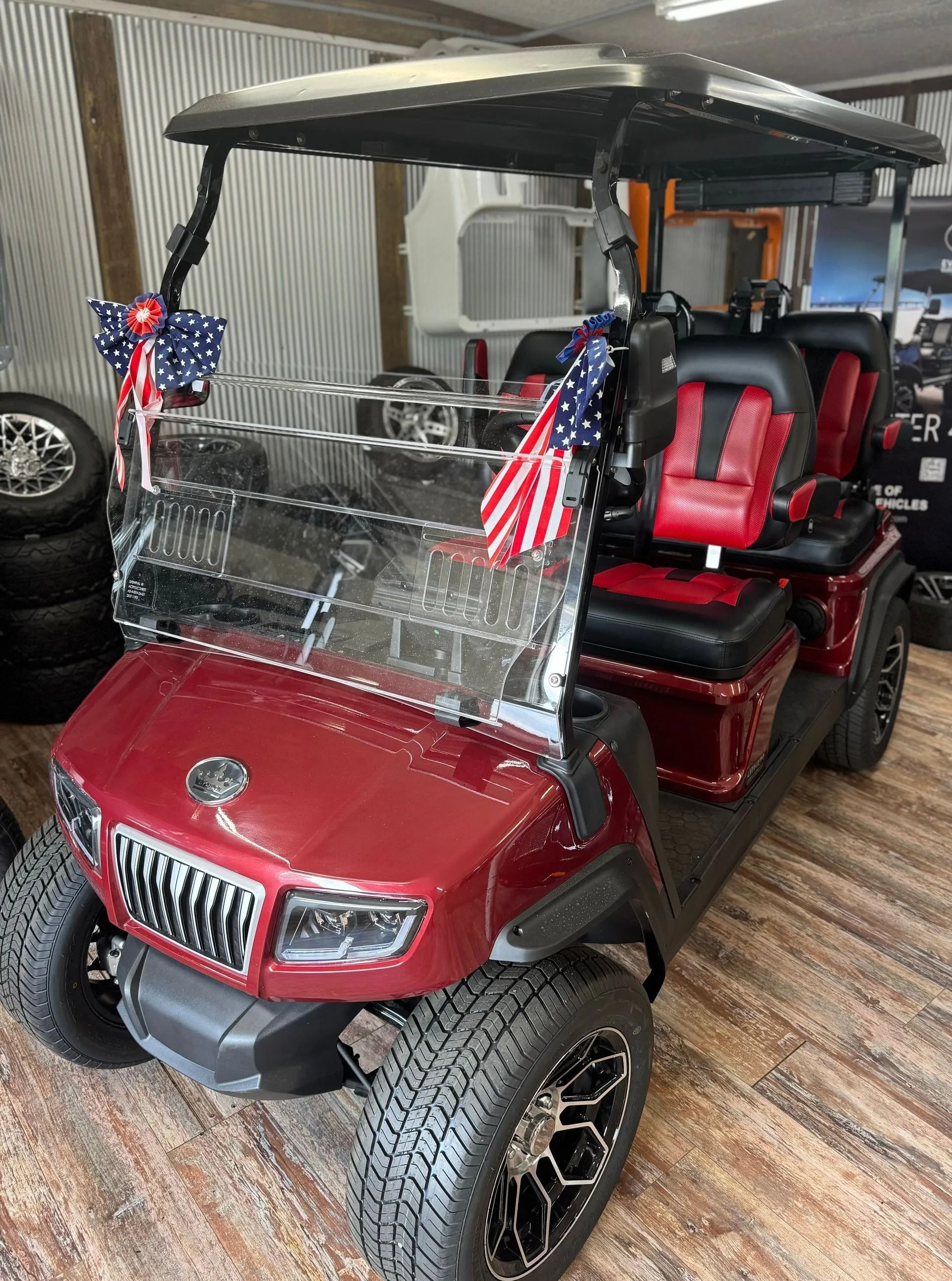 A red golf cart is parked in a garage with american flags on it.