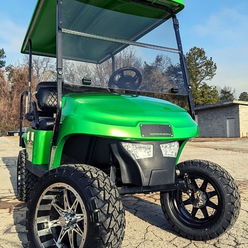 A green golf cart is parked on the side of the road