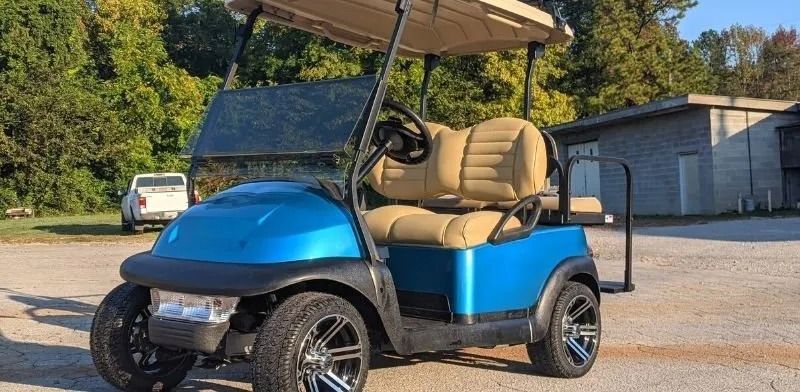 A blue golf cart is parked in a parking lot.