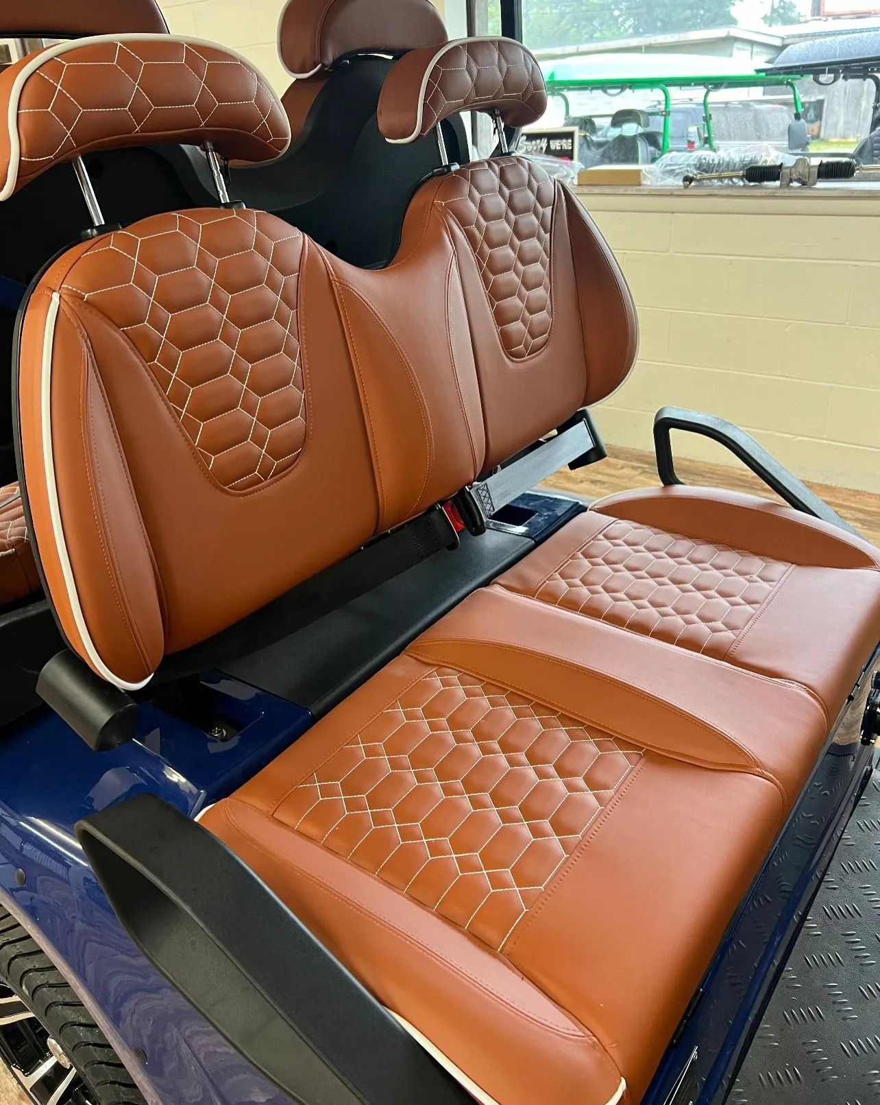 A blue golf cart with brown leather seats