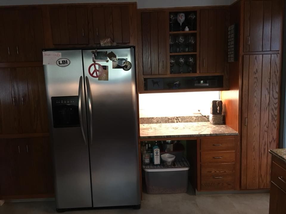 A kitchen with a stainless steel refrigerator and wooden cabinets.