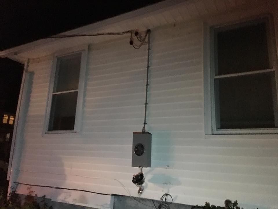 A white house with a box on the side of it at night.