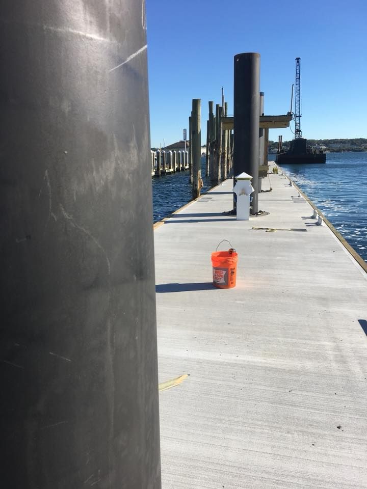 A bucket is sitting on a dock next to a pole.