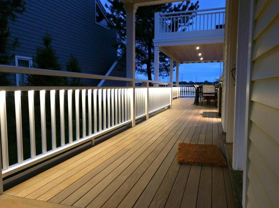 A deck with a white railing and lights on it