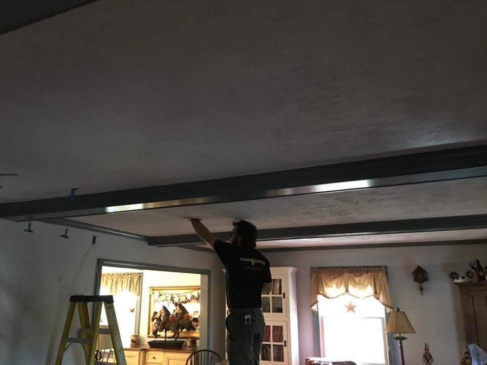 A man is working on a ceiling in a living room