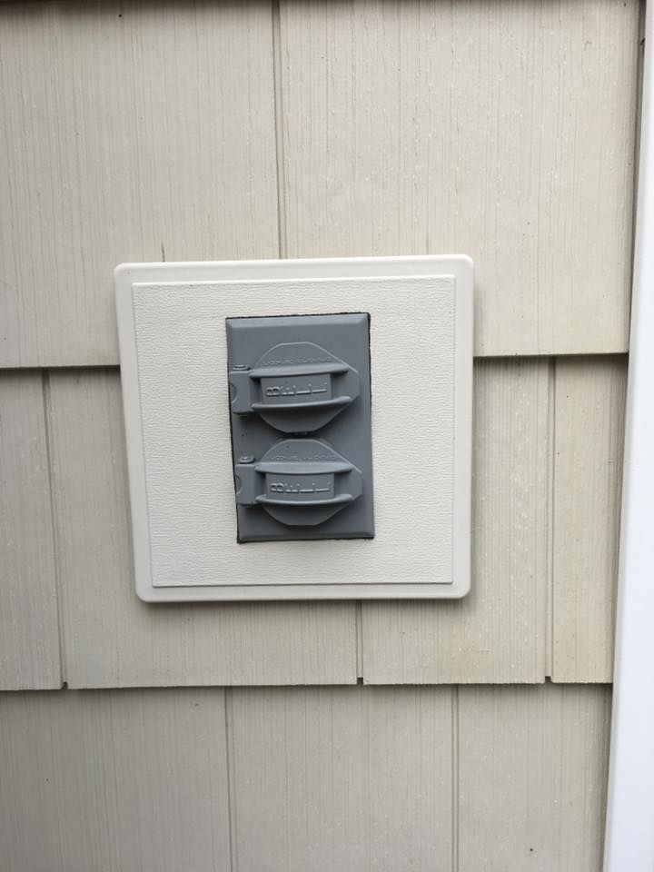 A gray electrical outlet on the side of a house.