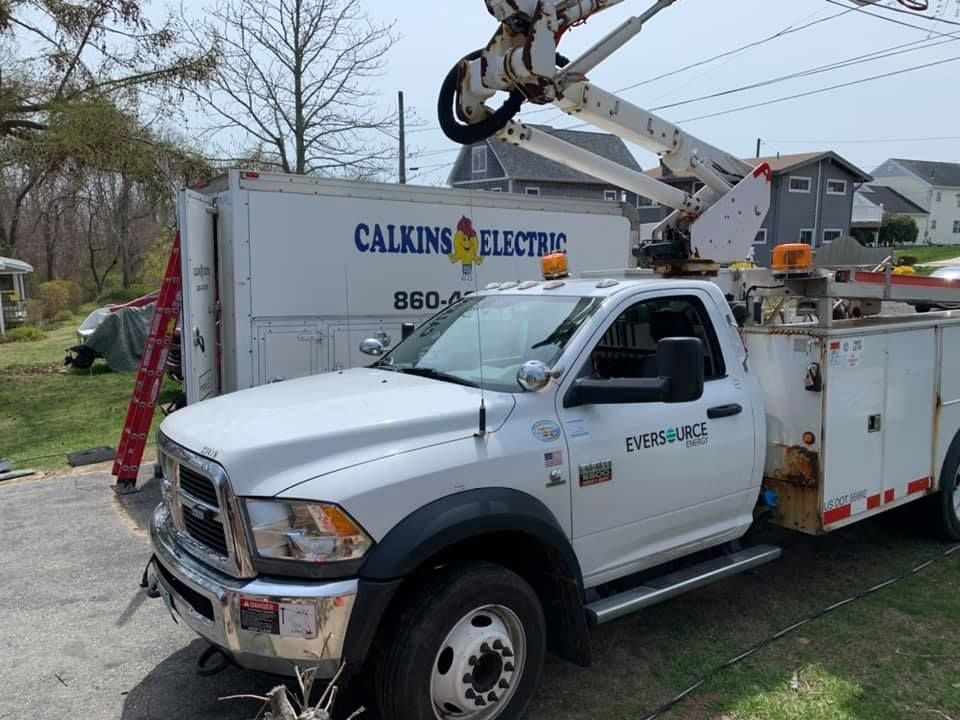 A white truck is parked in front of a building that says calkins electric