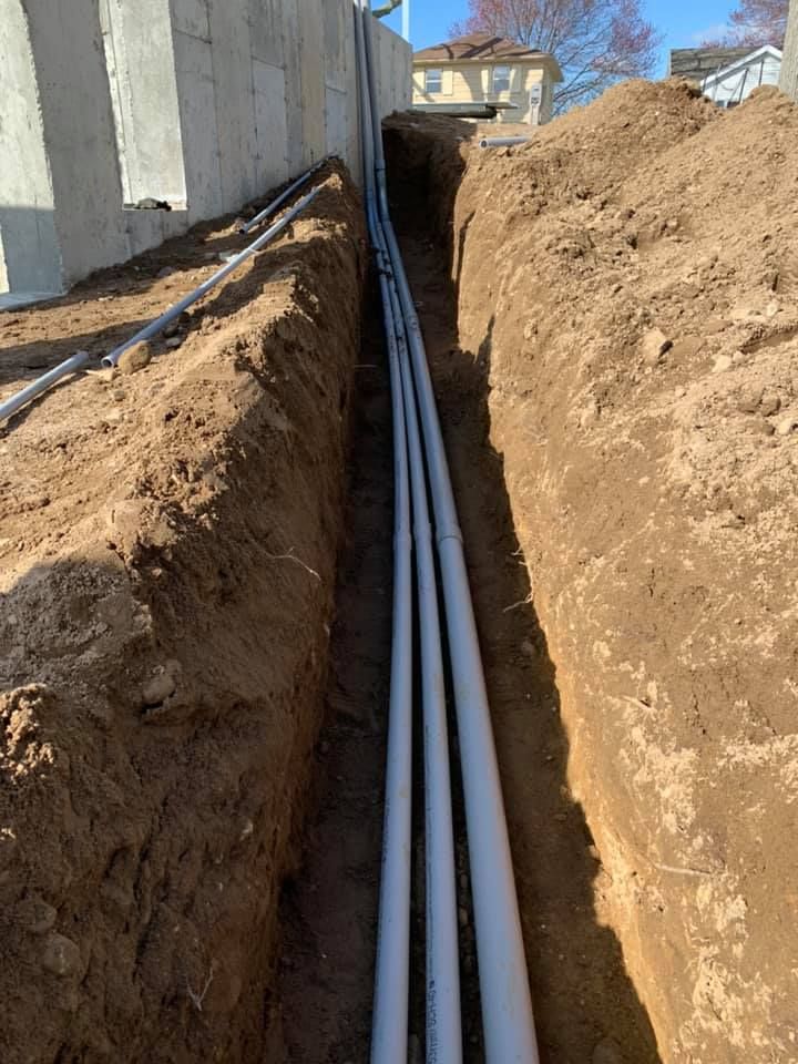 A bunch of pipes are being installed in a trench.