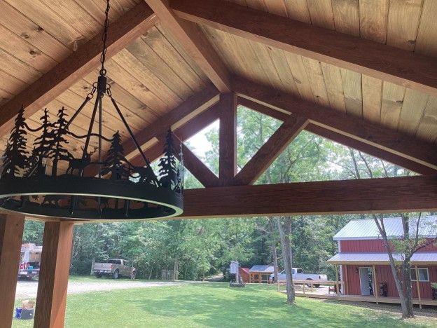 Wooden pavilion ceiling with holiday garland, overlooking a rural yard and red barn