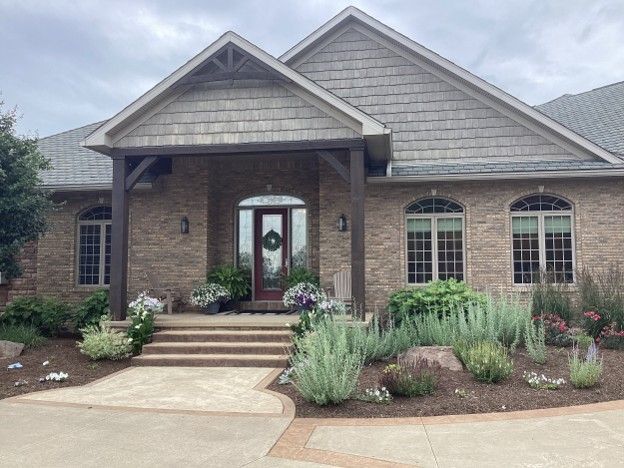 Brick house with a covered front porch, arched windows, and landscaped front yard.