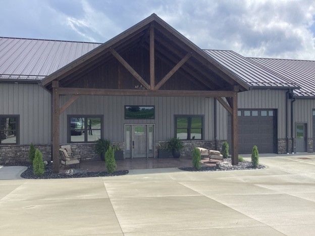 Front entrance of a modern building with a covered porch, stone columns, and a metal roof