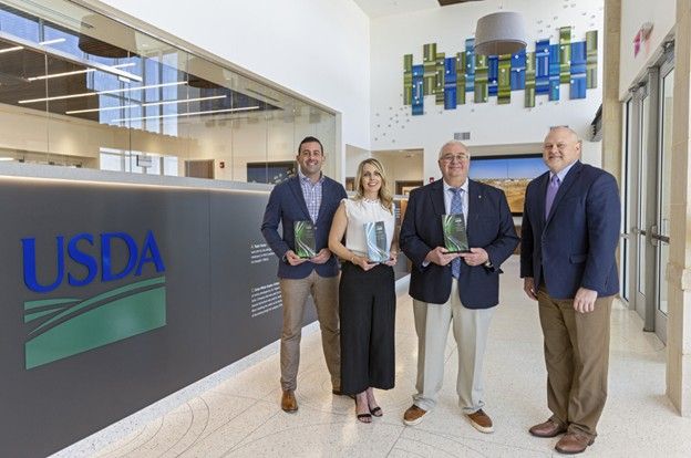 A group of people are standing in front of a sign that says usda.