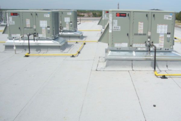 A row of air conditioning units on top of a roof