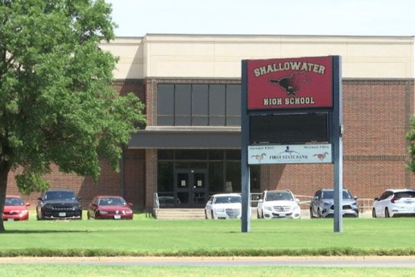 A sign for swallowwater high school is in front of a brick building