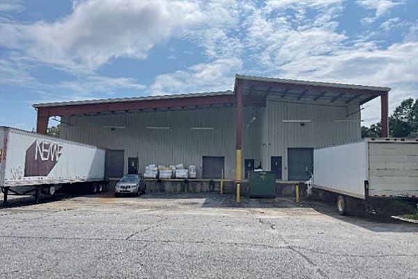 A warehouse with a lot of trucks parked in front of it.