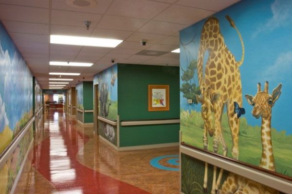 A hospital hallway with giraffes painted on the walls
