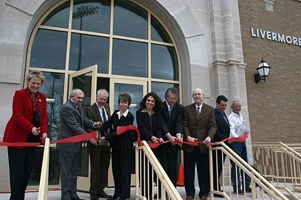 A group of people are cutting a red ribbon in front of a building that says livermore
