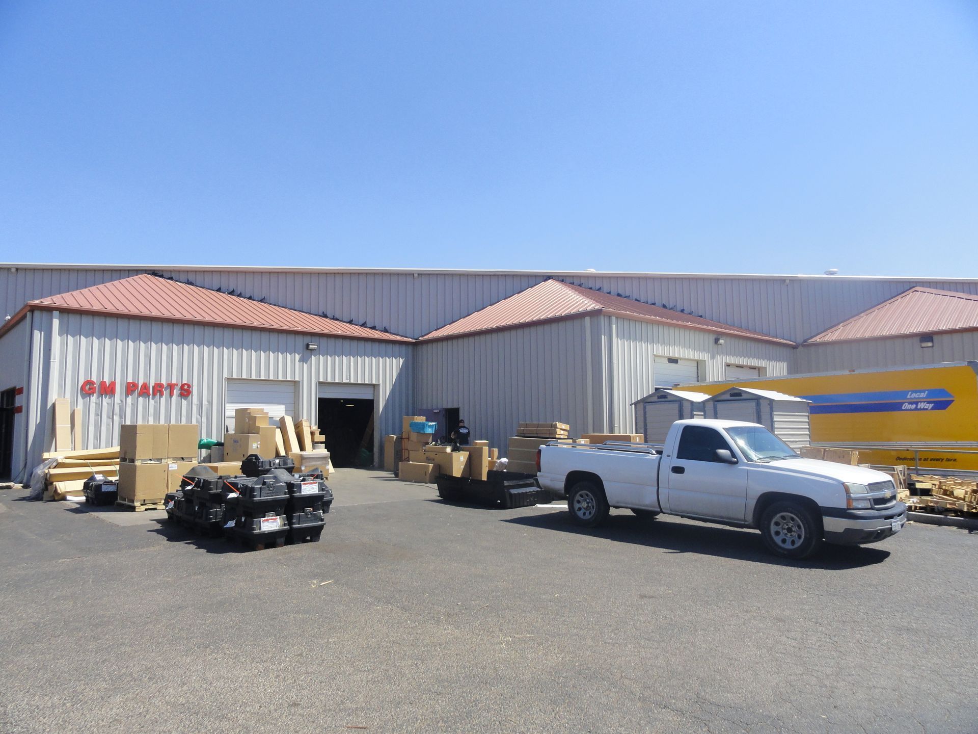 A white truck is parked in front of a building that says auto parts