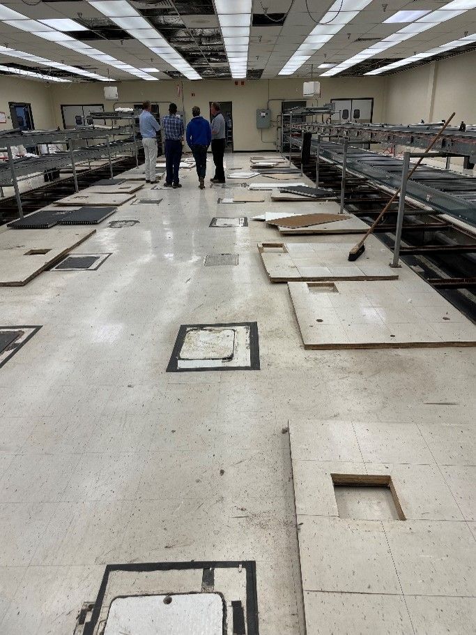 A group of people standing in a room with a lot of tiles on the floor