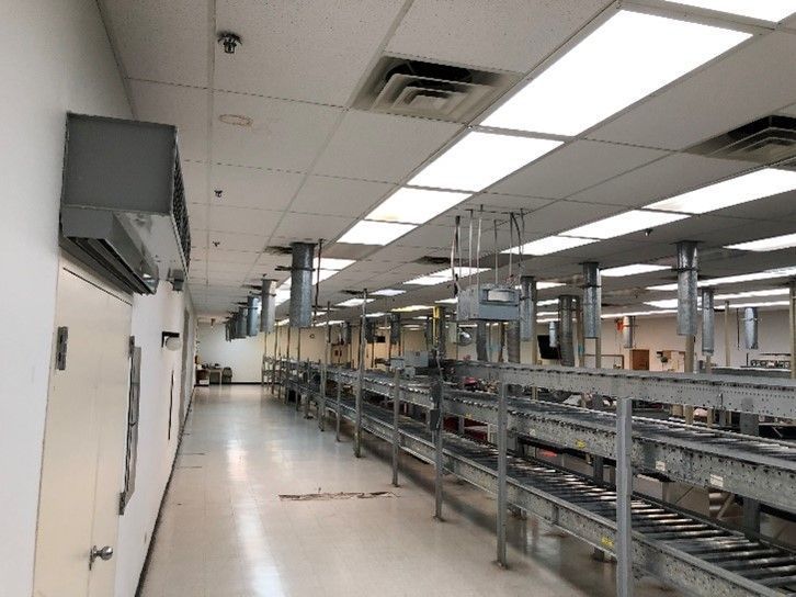 A long hallway in a factory with conveyor belts and lots of lights.
