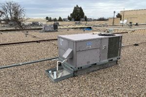A large air conditioner is sitting on top of a gravel roof.