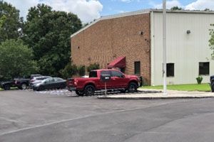 A red truck is parked in a parking lot in front of a building.