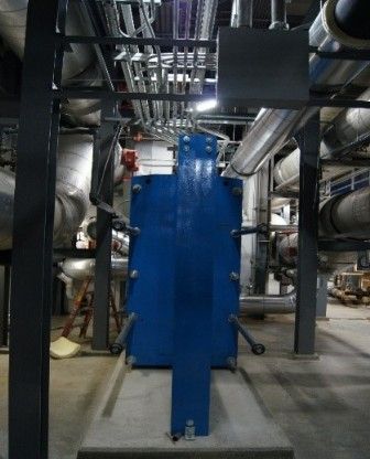 A blue machine is in a room with pipes and wires.