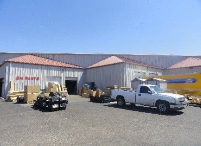 A white truck is parked in front of a building that says auto parts