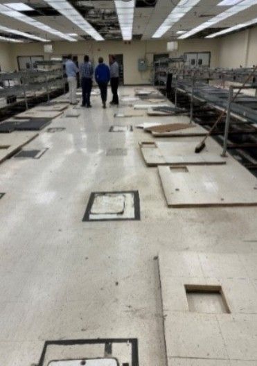 A group of people standing in a room with a lot of tiles on the floor