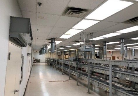 A long hallway in a factory with conveyor belts and lots of lights.