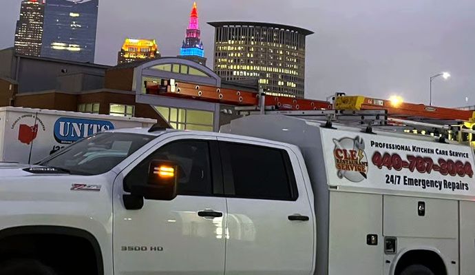 White service truck with city skyline in background; red, pink, and blue lighting on building.