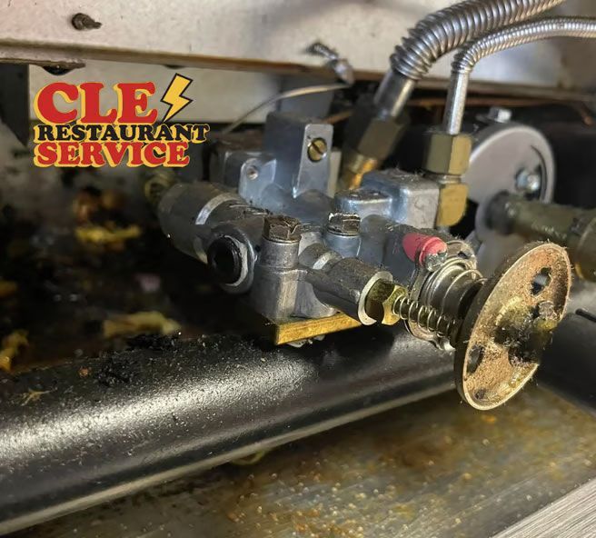 Close-up of a gas valve in a commercial oven, with grease and the CLE Restaurant Service logo.