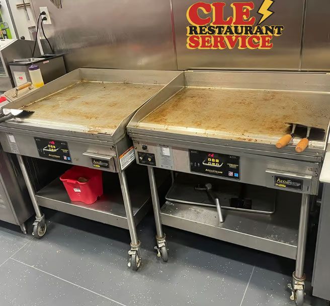 Two commercial griddles on rolling stands in a restaurant kitchen.