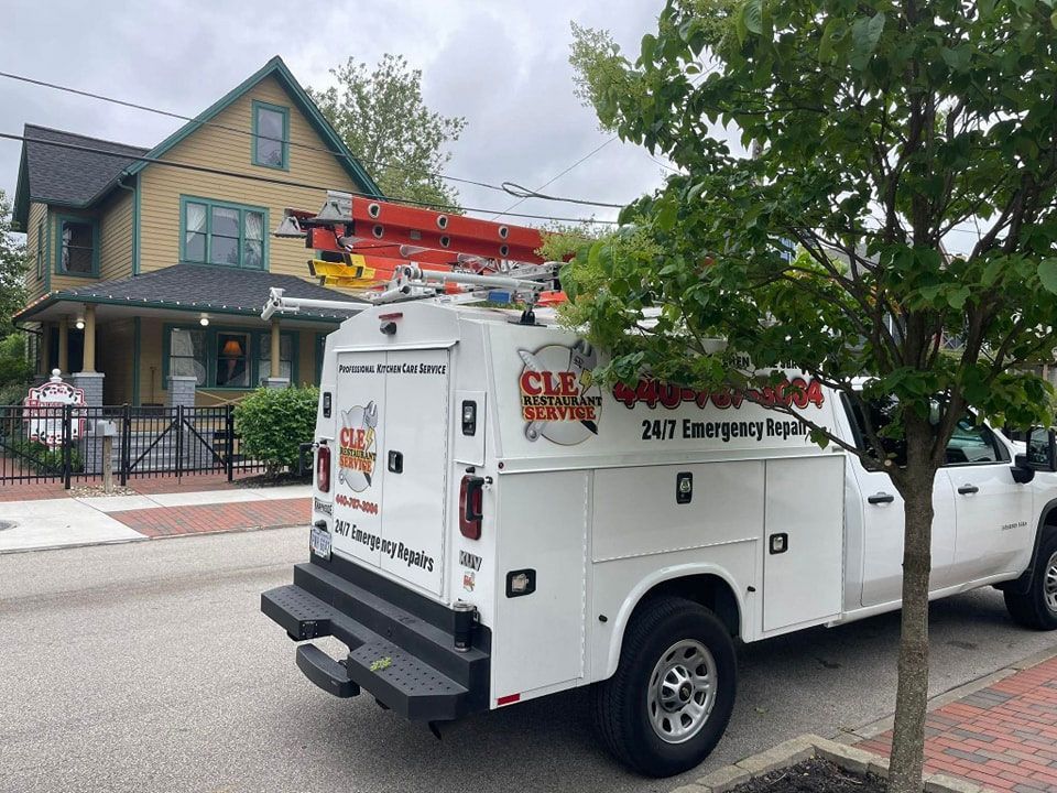 White service truck parked on street in front of a house; ladder on the roof.