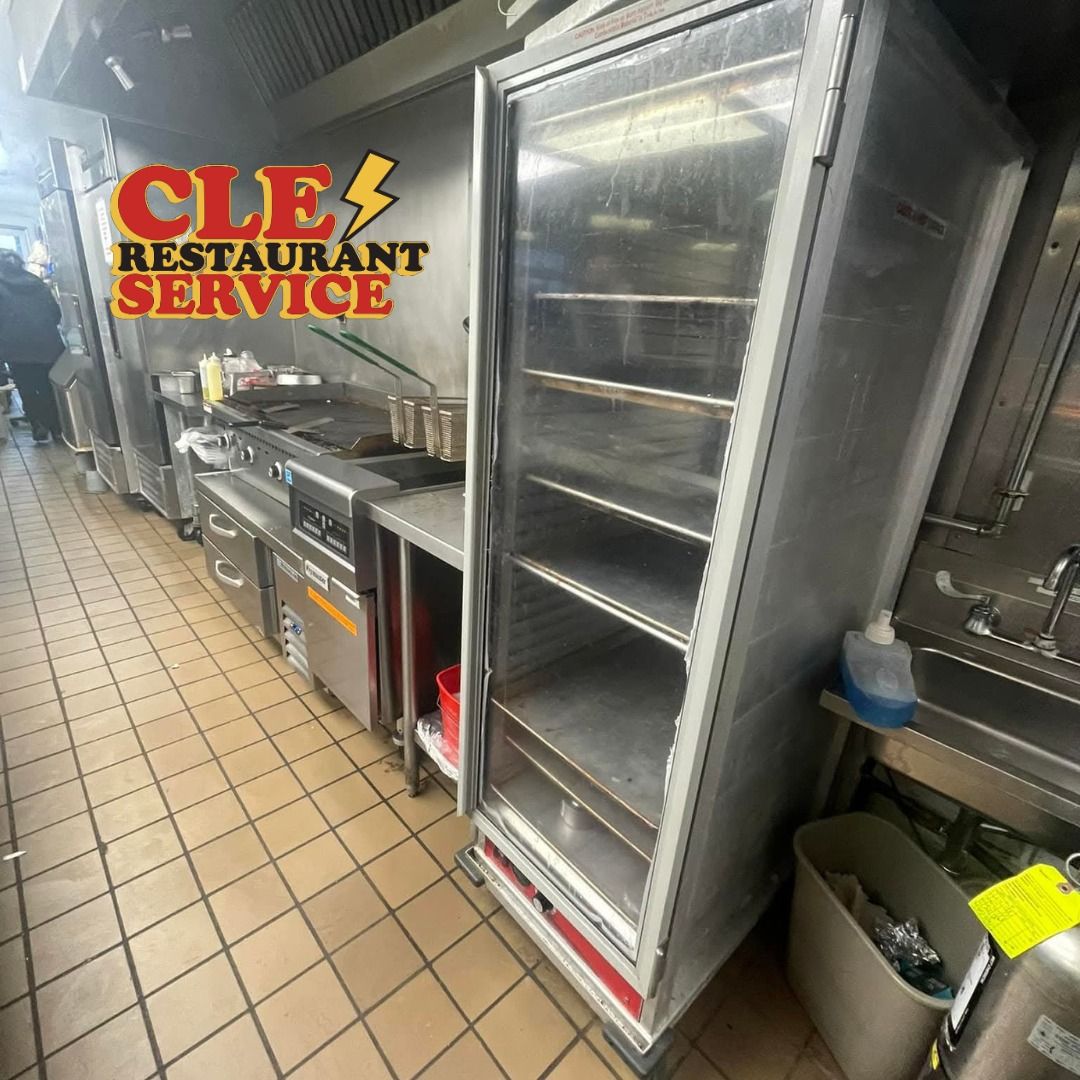 Restaurant kitchen with stainless steel equipment; open refrigerator, stove, sink.