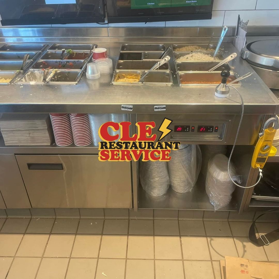 Stainless steel food prep station at a restaurant. Includes ingredient bins, storage, and warming lights.