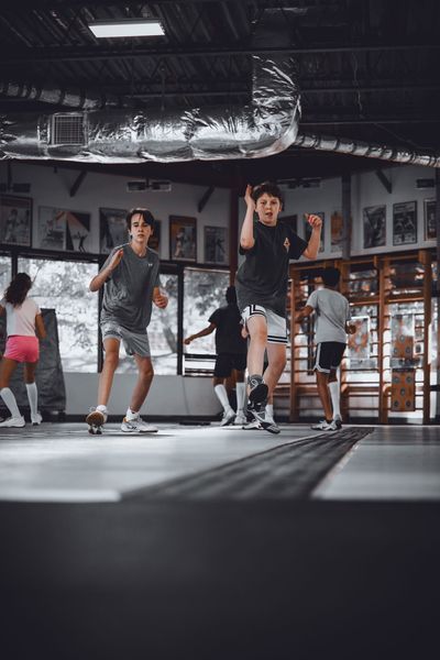 People jumping and running in a gym with wooden bars and large windows.