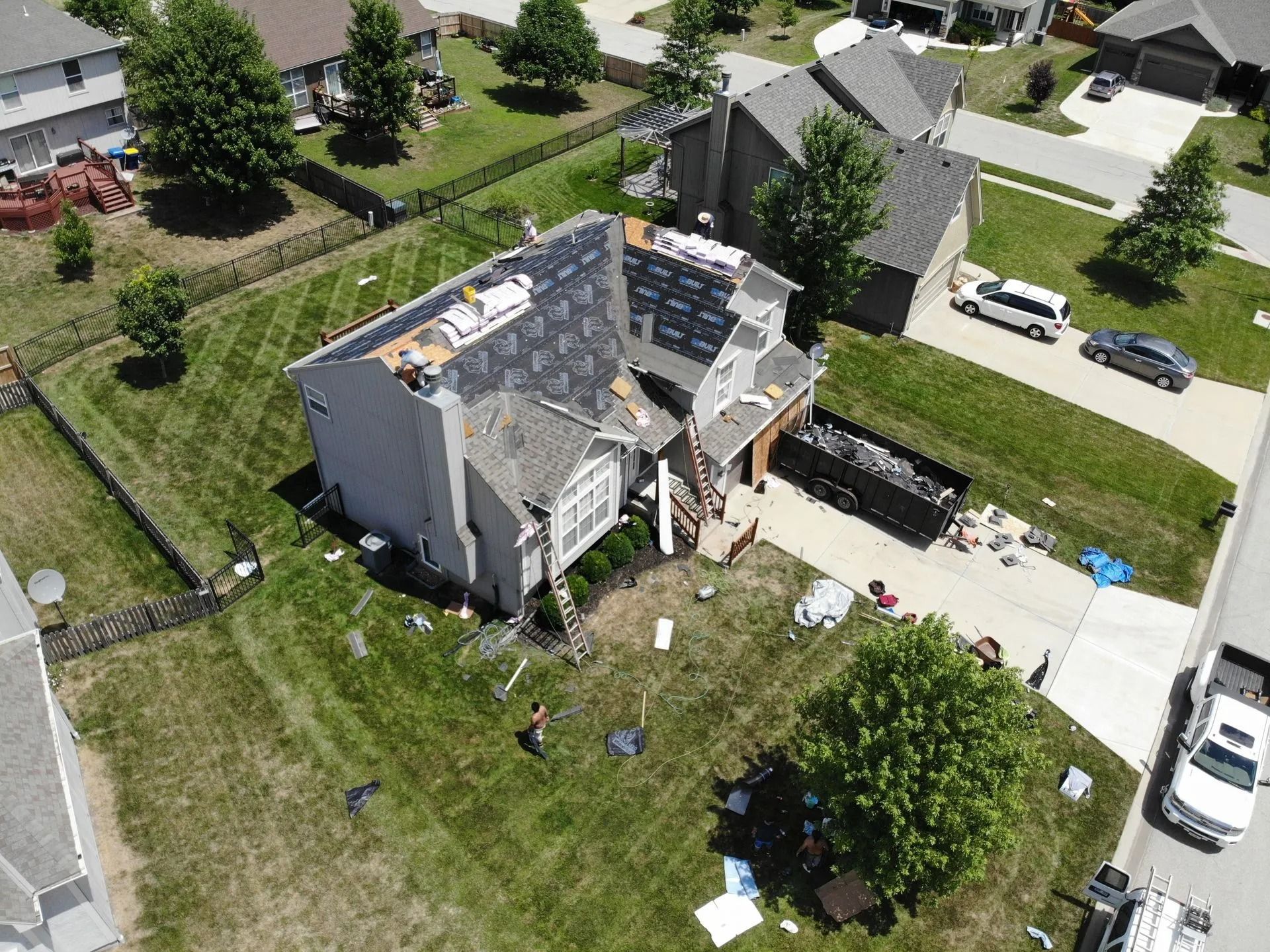Aerial view of a house with severe roof damage; debris scattered across the lawn.