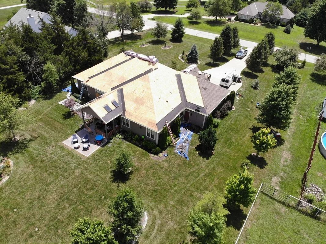 Aerial view of a house with roofing in progress on a sunny day.