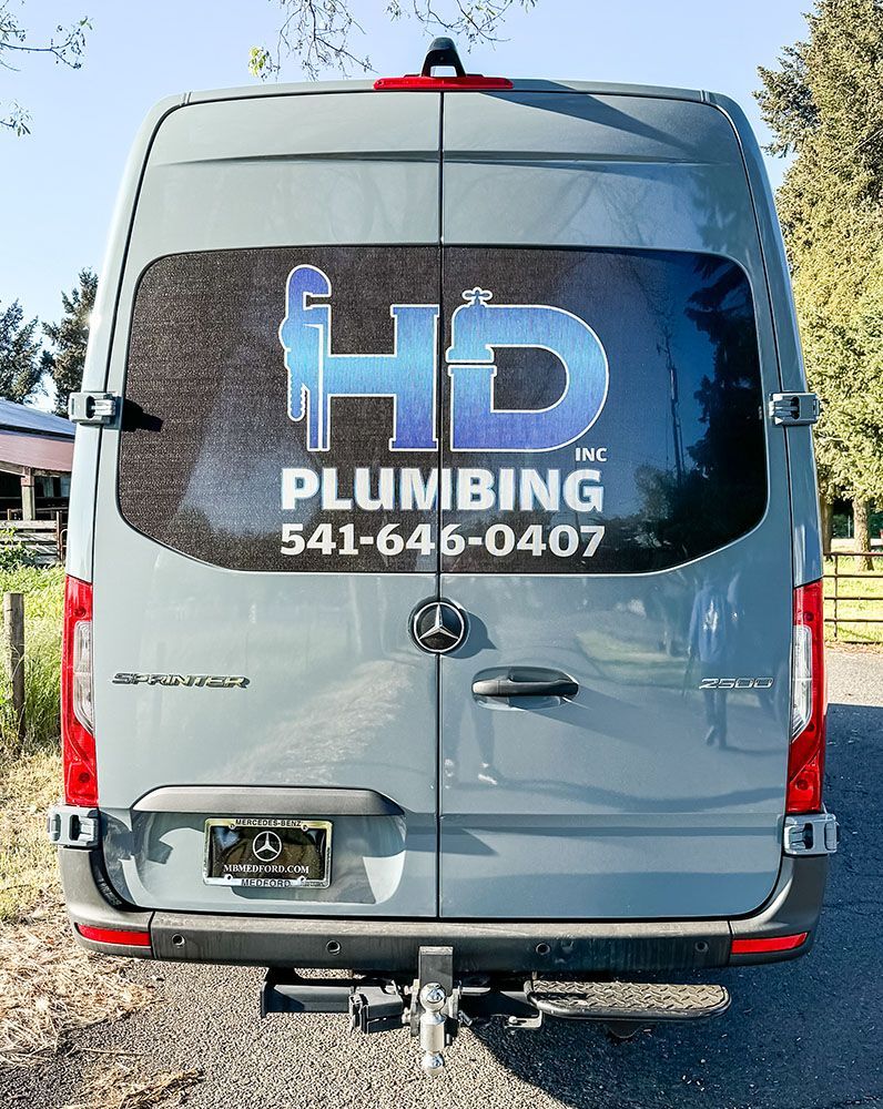 A gray van with the word plumbing on the back window